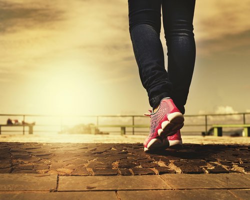 A person wearing clean lifestyle sneakers walking down a tree-lined sidewalk in Barcelona