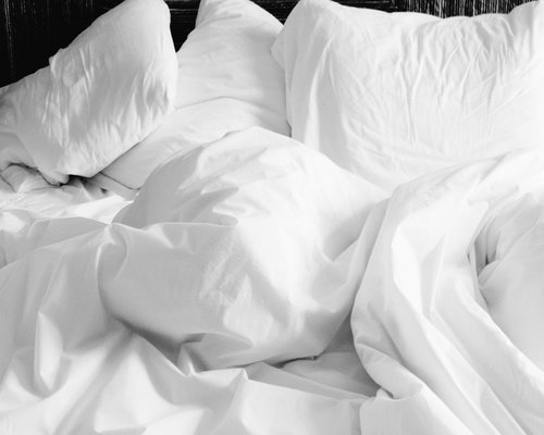 A quiet bedroom atmosphere with soft fabrics on the bed symbolizing a healthy night rest routine